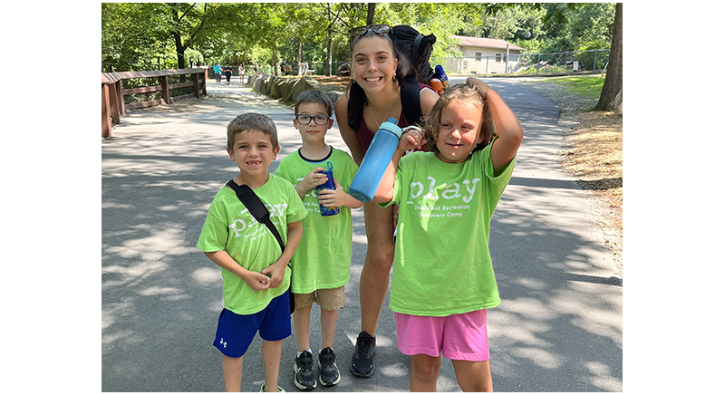 three smiling discovery campers with counselor on a field trip